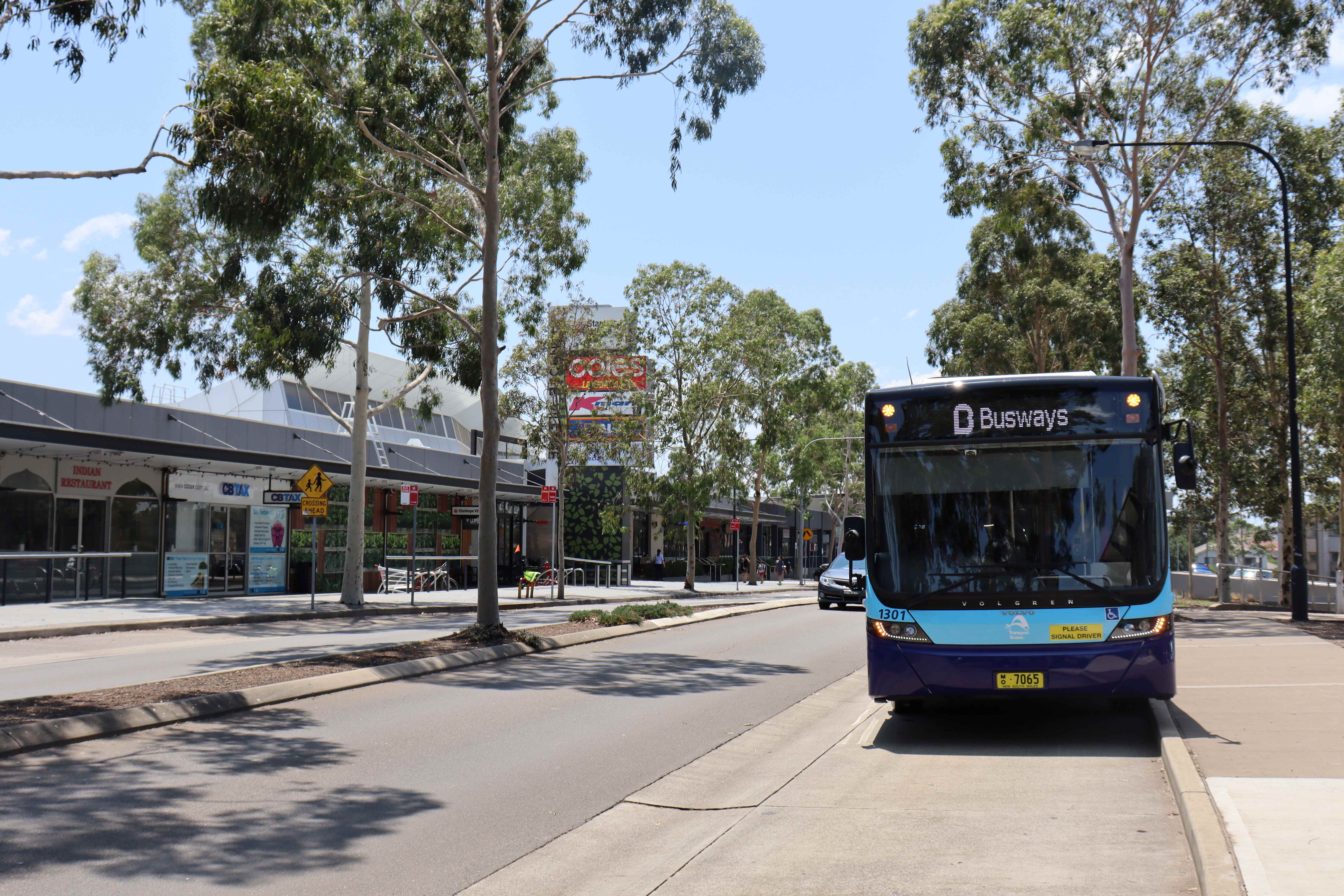 Blue bus pulling up to bus stop