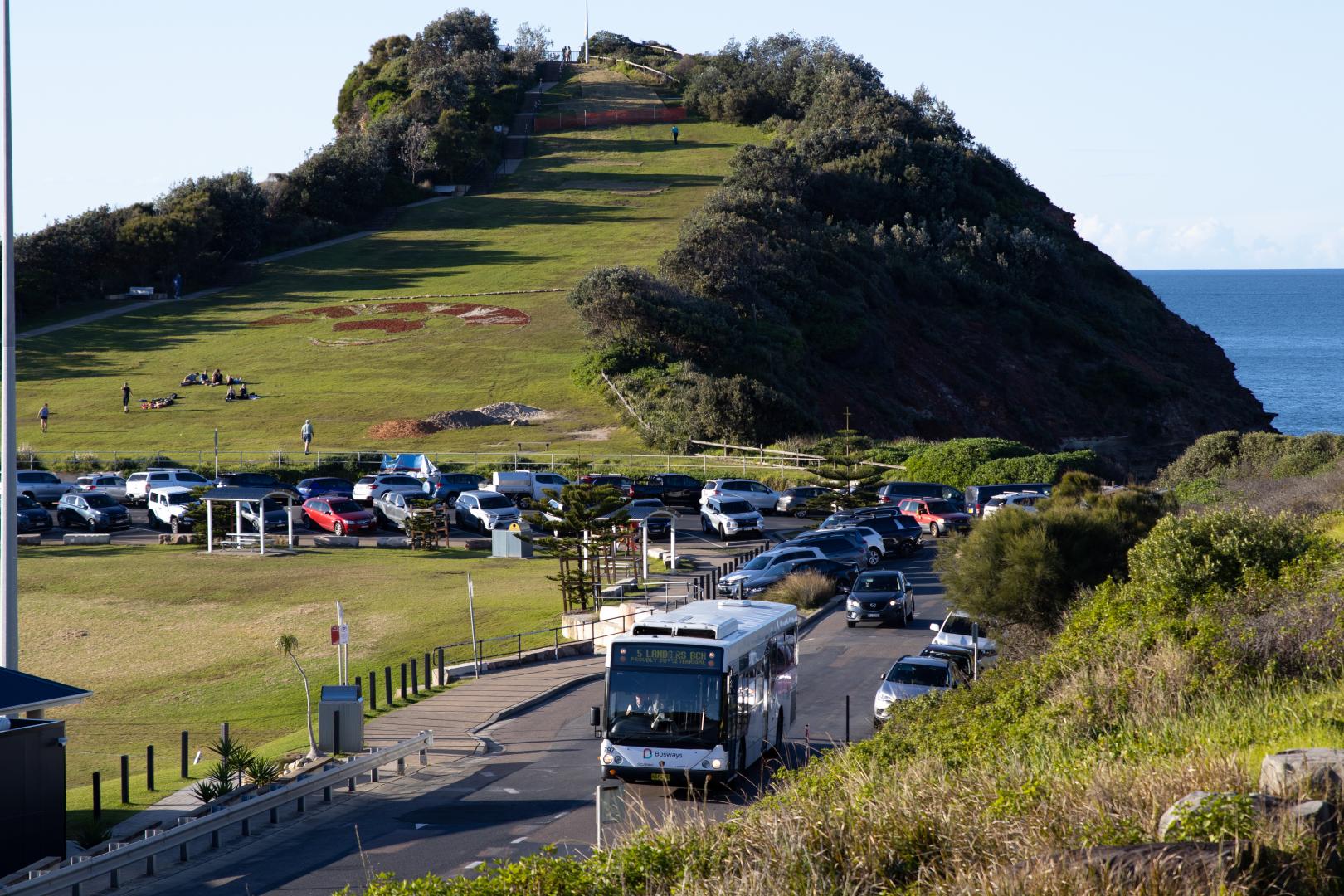 busways bus driving on road with headland in the background
