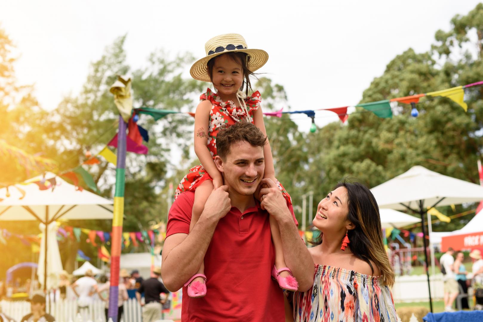 Dad with daughter on his shoulders walking through community event