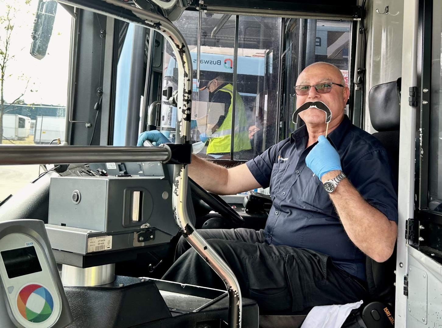 Bus driver holding movember prop 
